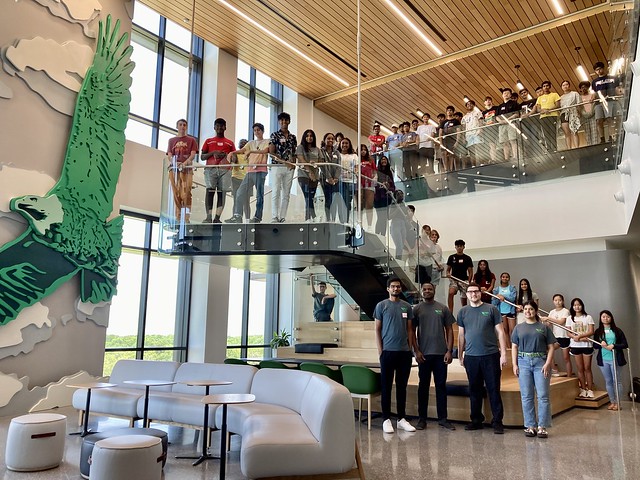 Group of students posing at staircase in Frisco Landing campus.