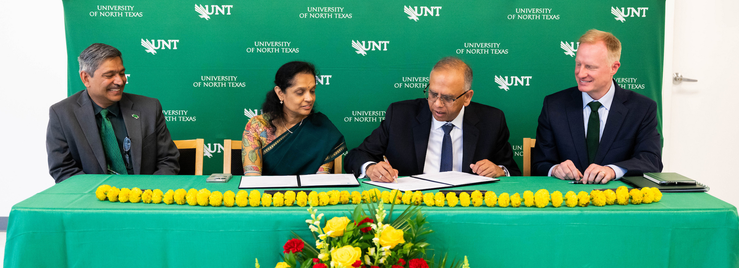 Dr. Vikas and Anuradha Sinha signing at table with Dean Kinshuk and President Keller.