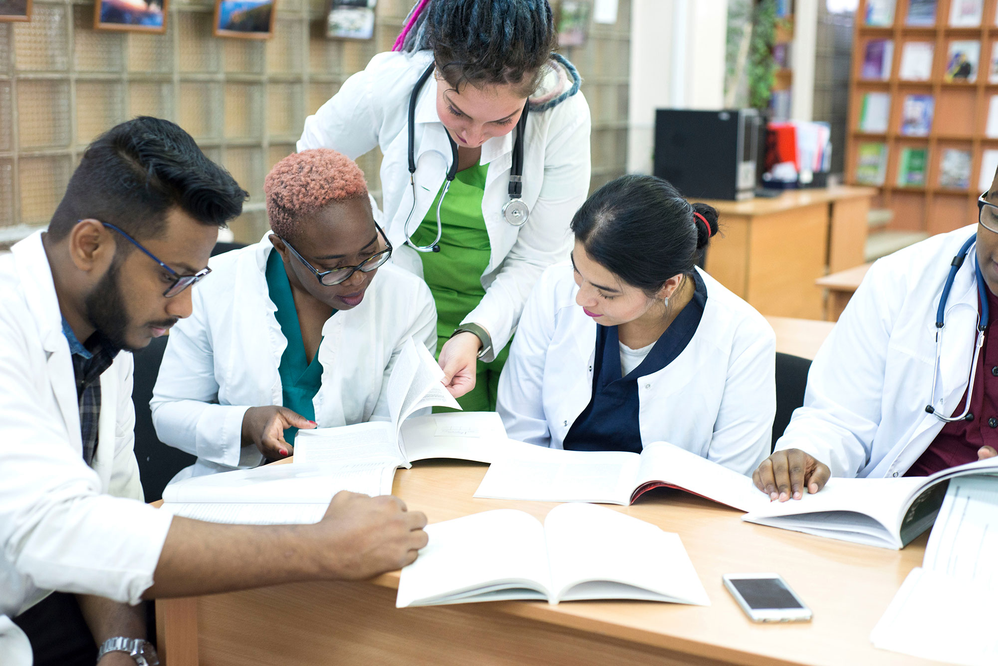 Students in lab coats studying and reading books together.