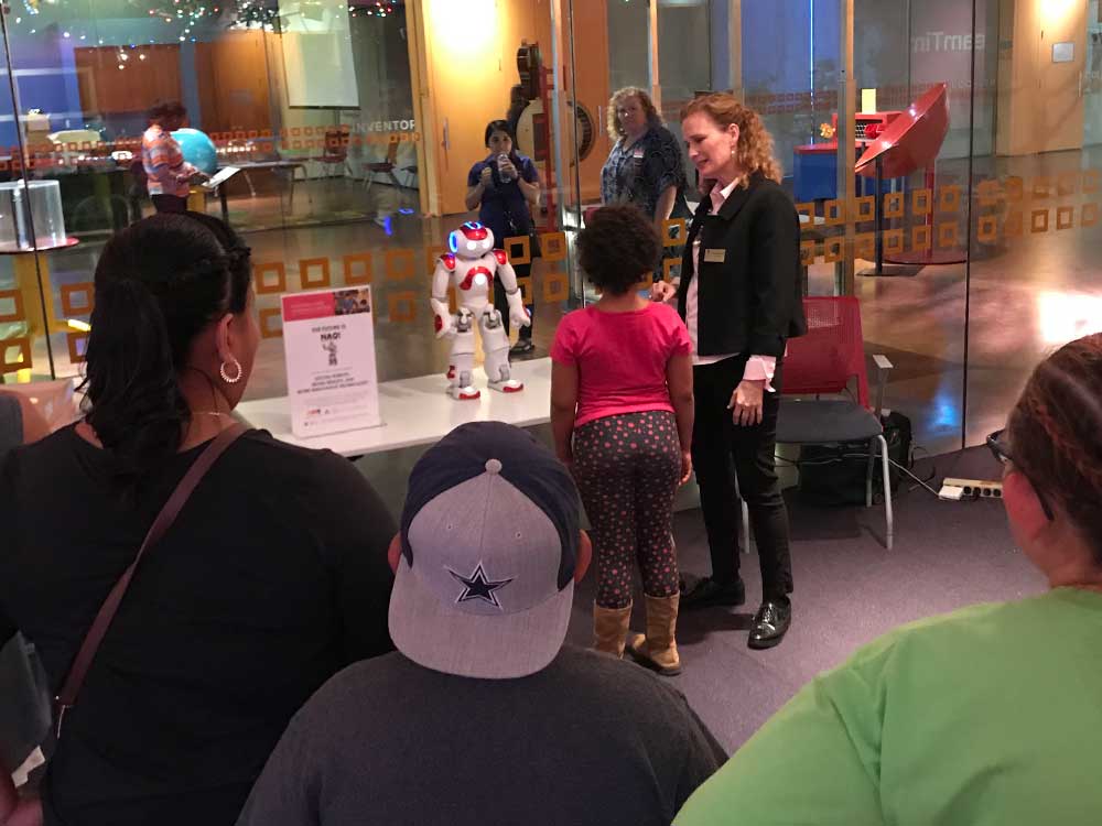 Girl standing in front of a robot.