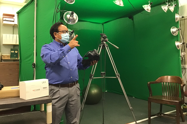 LT Faculty standing in front of green VR screen setup.