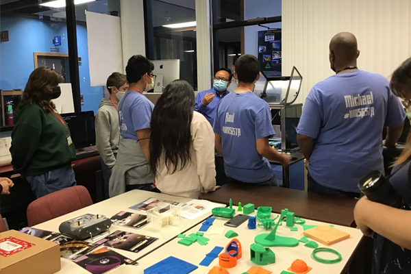 LT Faculty standing in front of middle school students in a 3D printing lab.