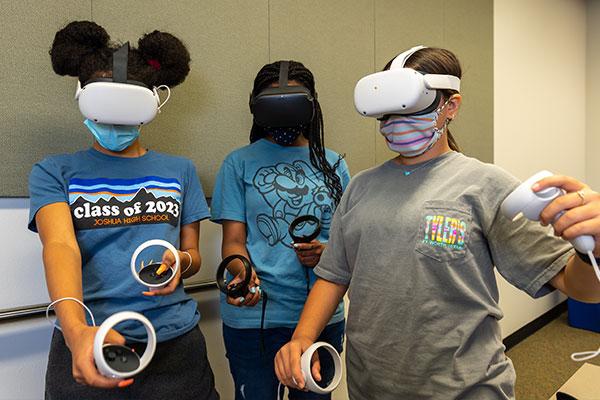 Three female grade school students holding VR goggles.