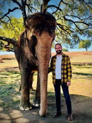 Joshua Ryan standing next to an Elephant.